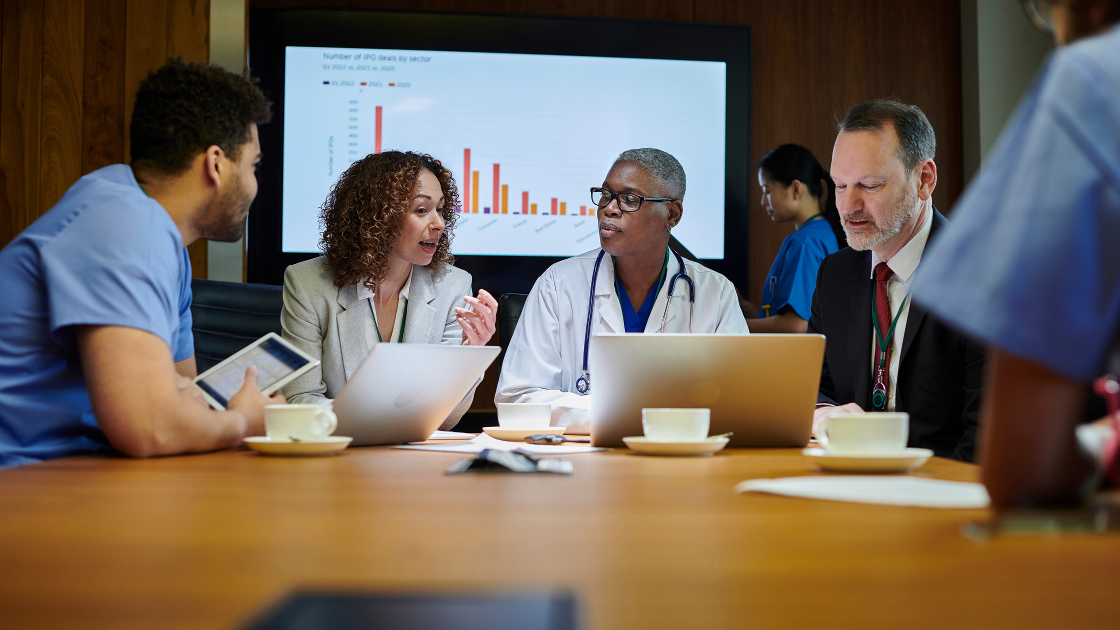 Image of four medical professionals sitting around a table with a presentation graph in the background